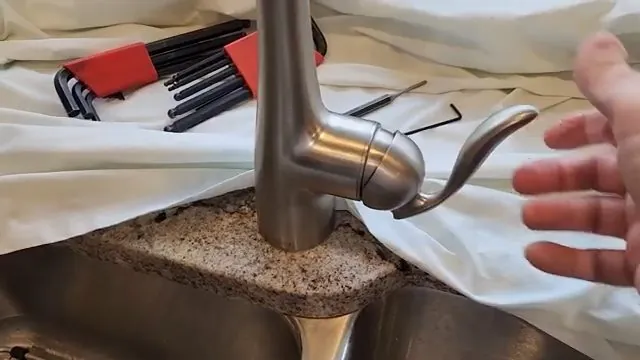 Stainless mixer tap partly taken apart on a towel beside a set of hex keys