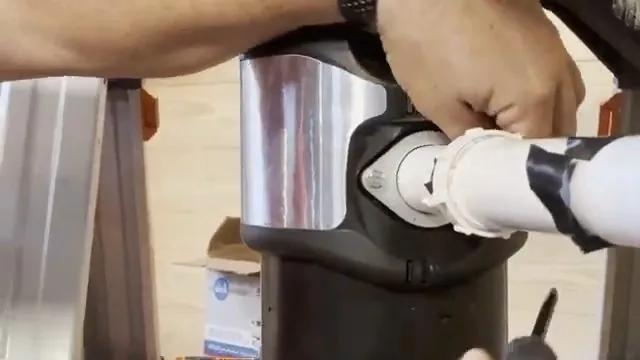 Close view of the white discharge pipe and clamp where it joins a garbage disposal