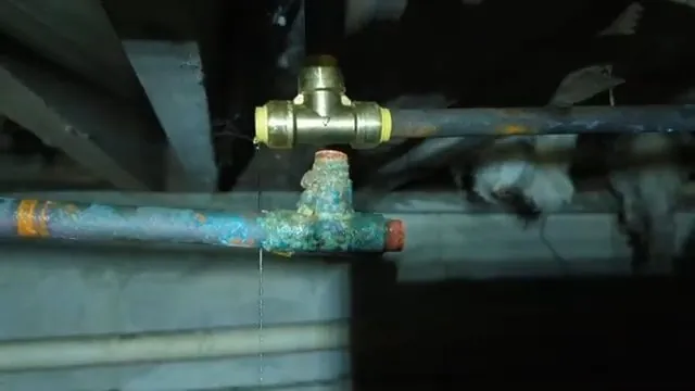 Brass fitting joining copper pipes under a floor, with insulation beside it