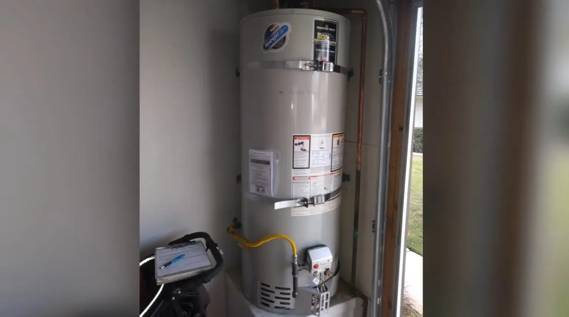 Gas water heater with its yellow flex and drain in a utility closet