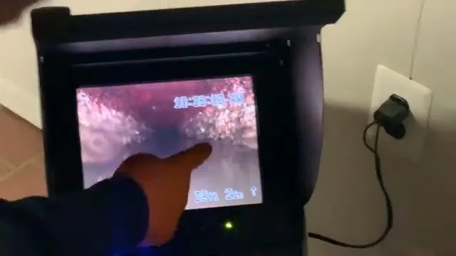 Hand pointing at a monitor showing the inside of a pipe, with a depth counter on screen