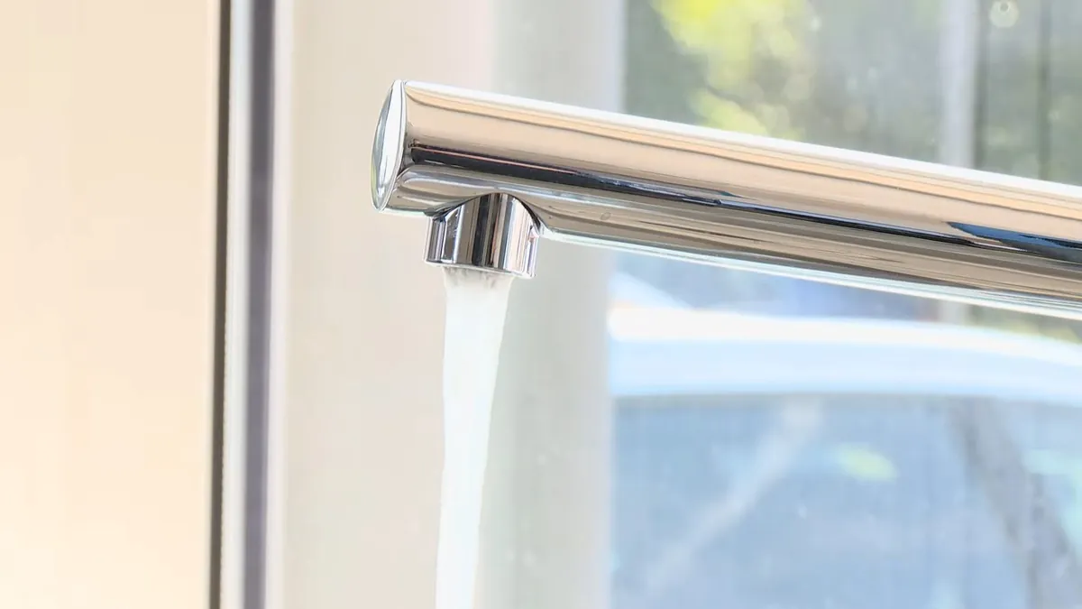 Water running from a chrome kitchen tap beside a window