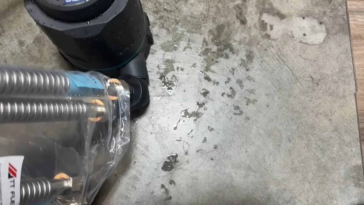 Stainless corrugated gas connectors in packaging beside a black fitting on a concrete floor