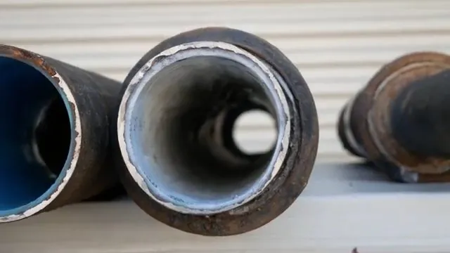 End view of black pipe sections with a cured white and blue liner lining the inside of the bore