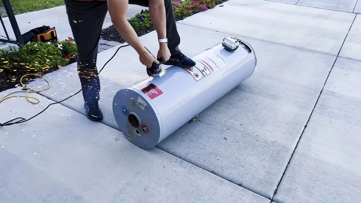 Person standing at a new tank water heater lying on its side on a concrete drive