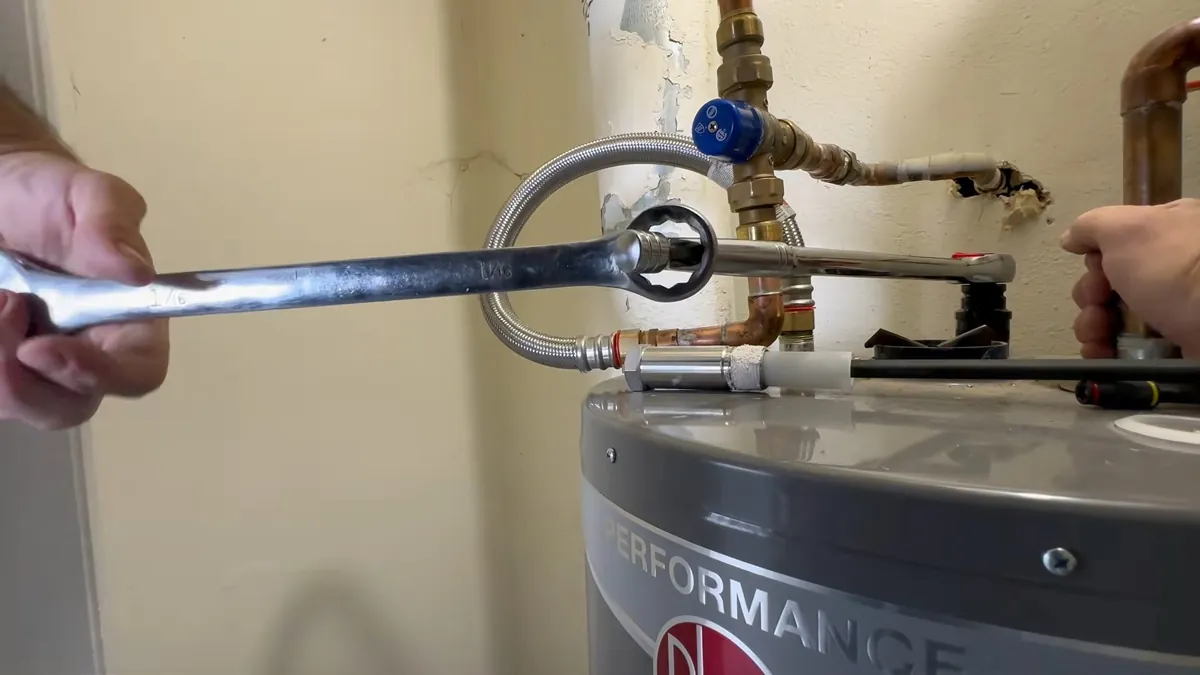 Wrench tightening a flexible water connector on the top of a tank water heater